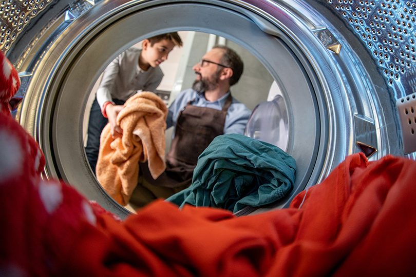 Son helping father to wash laundry