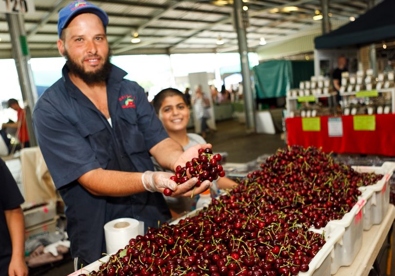 Man holding handful of cherries at market