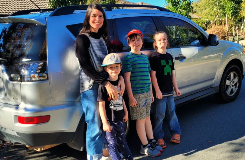 Woman and three children next to a car