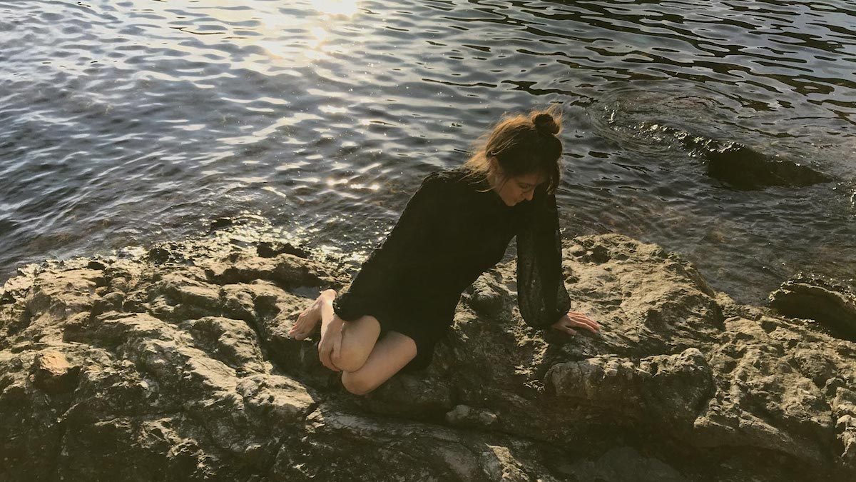 Woman siting on rocks near the ocean